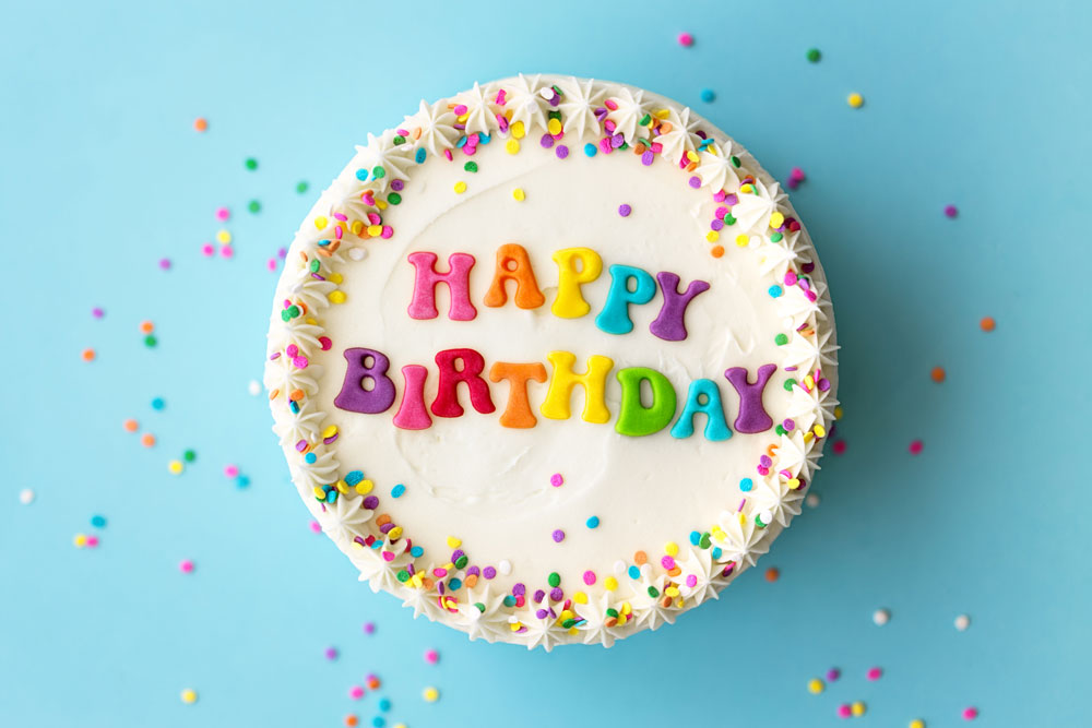 Birthday cake with sprinkles and happy birthday written in frosting