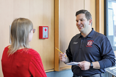 A firefighter with a pad and pencil speaking with a resident