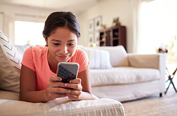 Teen girl with pink shirt looking at a cell phone