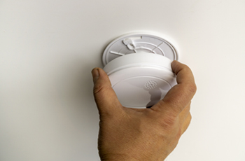 Photo of a hand installing a smoke detector