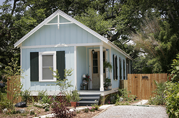 Small blue cottage-like house in a backyard