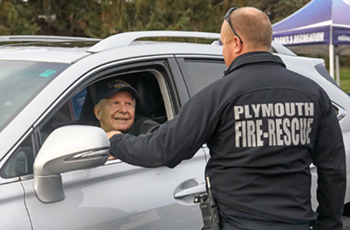 Photo of a person in a vehicle speaking with a person wearing a 