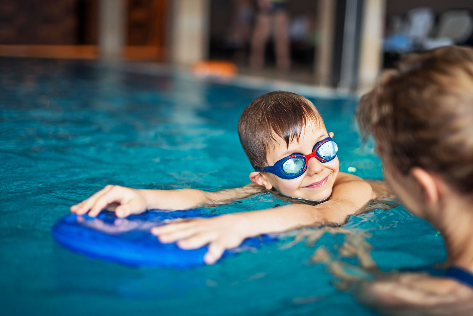 Child wearing goggles holding onto a float device at swim lessons