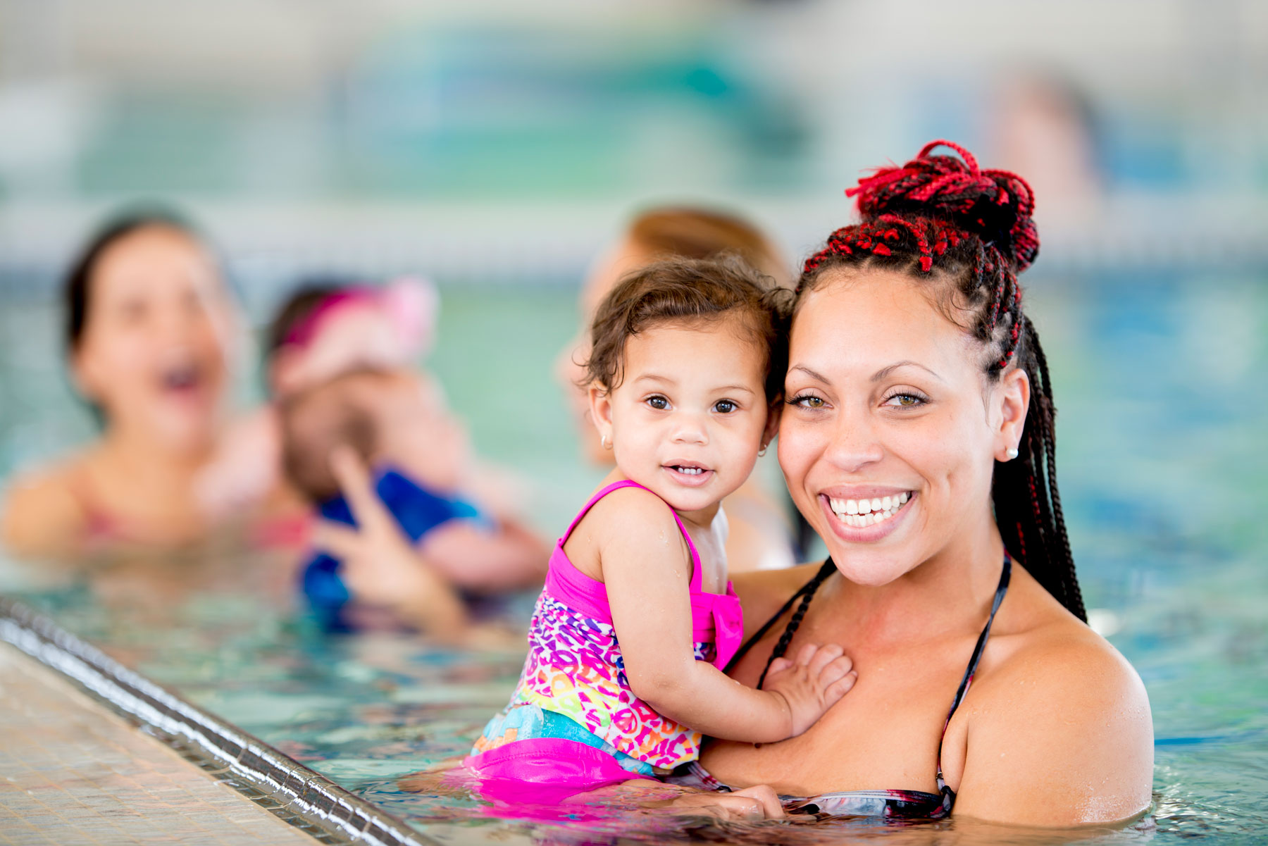 Image of an adult holding a young child at swimming lessons