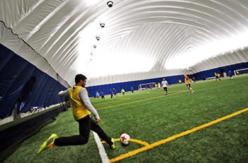 Soccer player kicking the ball inside the Plymouth Creek Center Fieldhouse dome