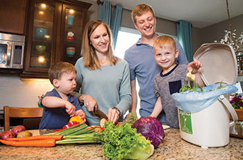 Family cutting vegetables and using organics recycling container for leftovers