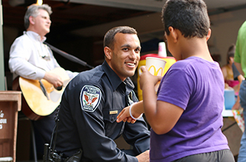 Child interacting with a police officer at a Night to Unite neighborhood block party