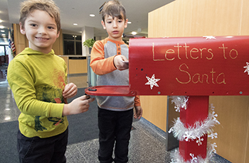 Children dropping off letters for Santa Claus in a big red mailbox at Plymouth City Hall