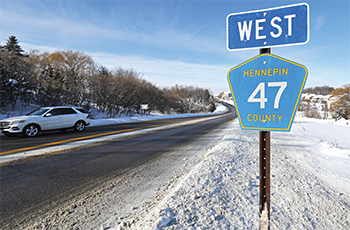 Hennepin County Road 47 street sign along the road in winter