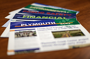 City newsletters on a table, featuring the Plymouth News