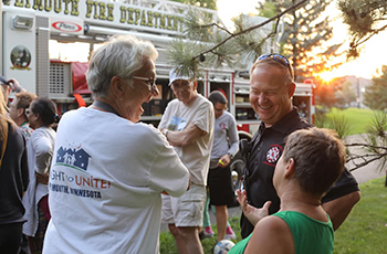 Plymouth firefighter sharing a laugh with a resident during a neighborhood Night to Unite block party