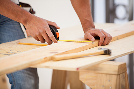 Person measuring a board on a work table