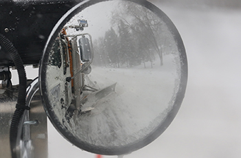 Photo of the mirror of a snow plow reflecting the vehicle while it's clearing the road in Plymouth