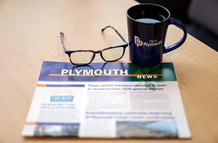 Plymouth News on table with coffee mug and glasses