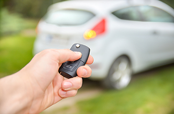 Closeup of a hand using a key fob to lock a car